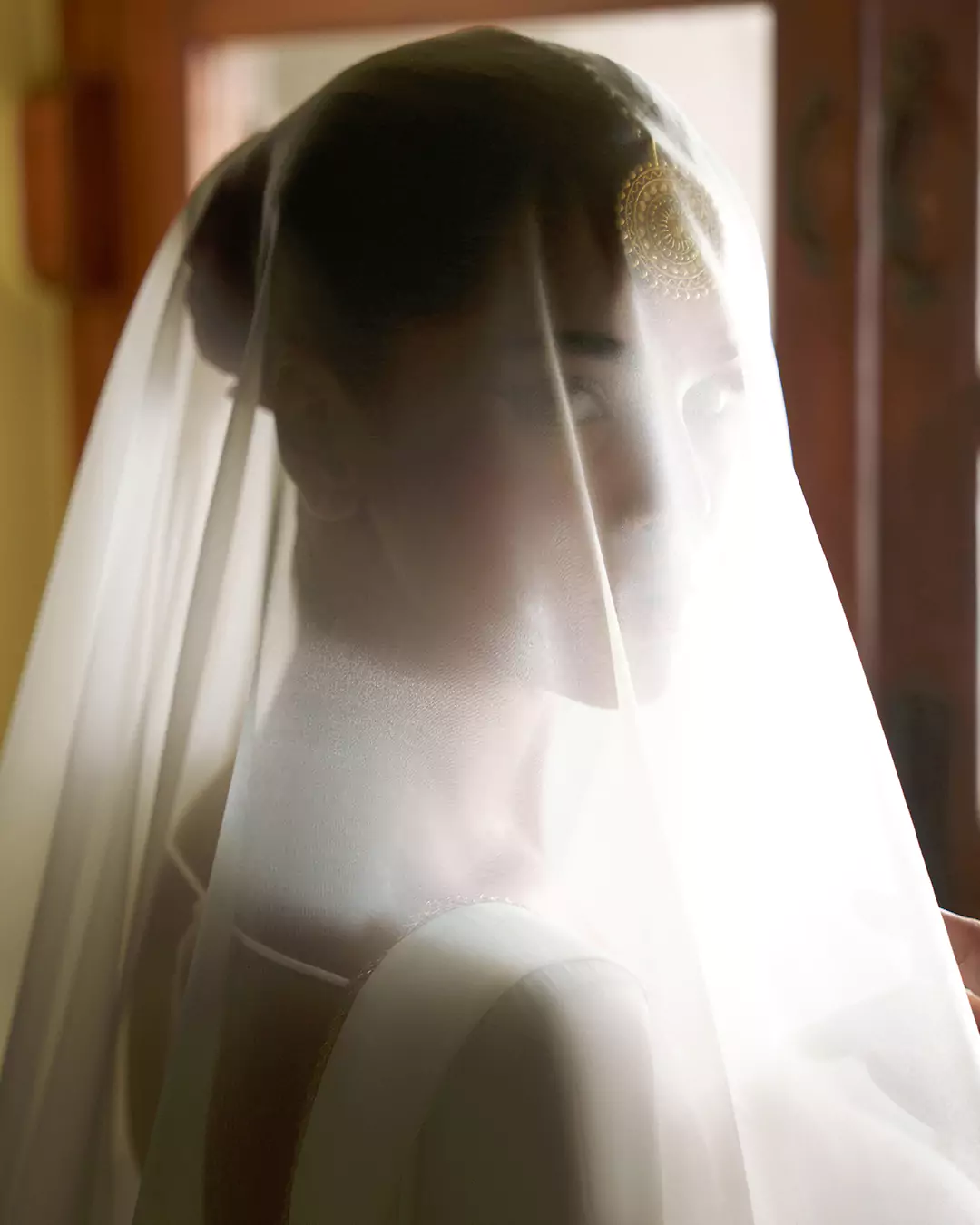 KALZARII Formals Collection 2026 editorial portrait featuring a model behind a softly illuminated sheer veil