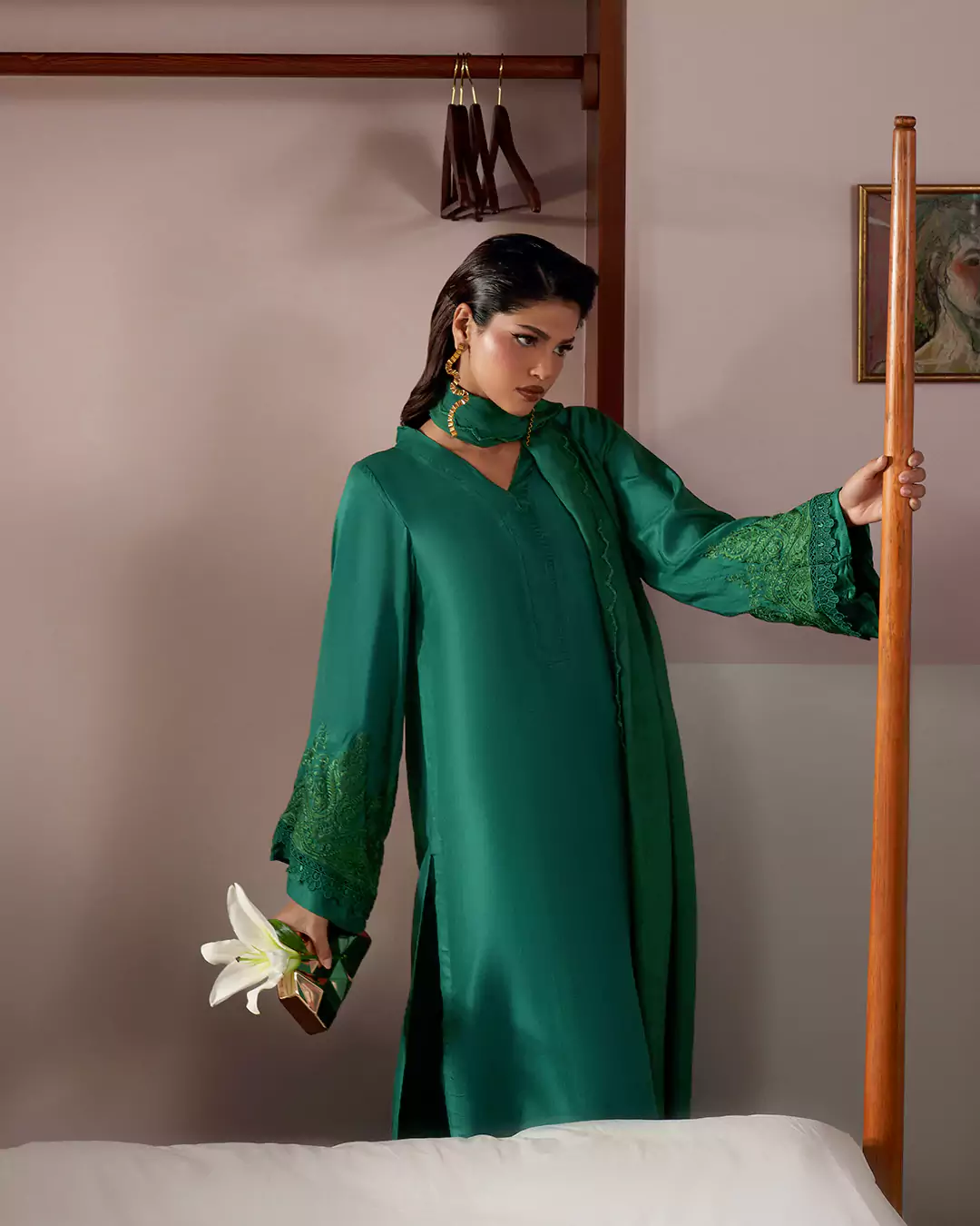 KALZARII 2026 formalwear look featuring a model in an elegant green outfit holding a flower indoors