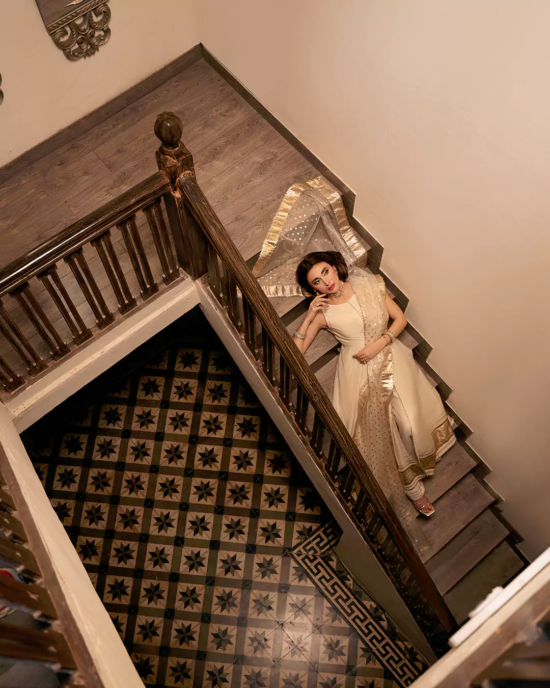 Overhead fashion photograph of a model wearing an off-white outfit while lying on a staircase for the AKKS by Attya campaign.
