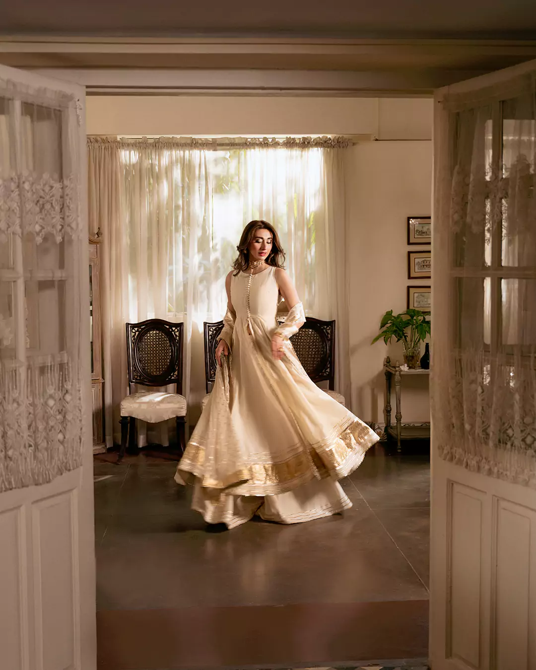 Model wearing an off-white outfit while facing the camera in a classic drawing room for the AKKS by Attya campaign.